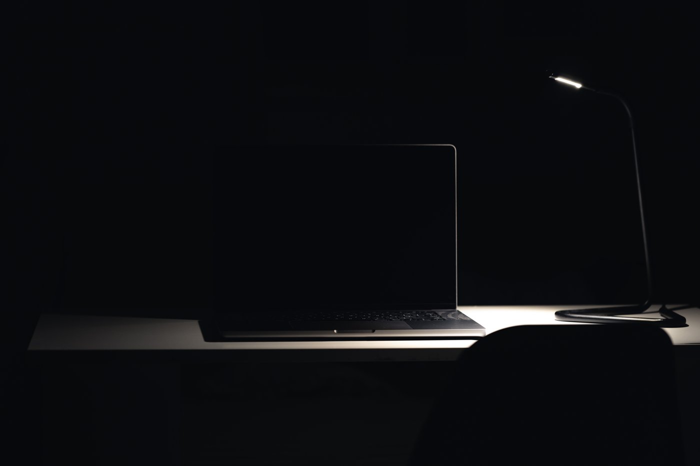 A laptop displaying a confidential executive report on screen in a dark room at night