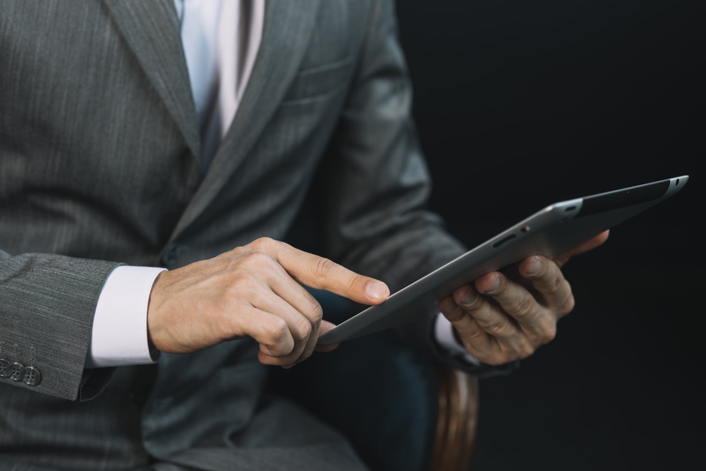 A business advisor in a suit reviewing review findings on a tablet